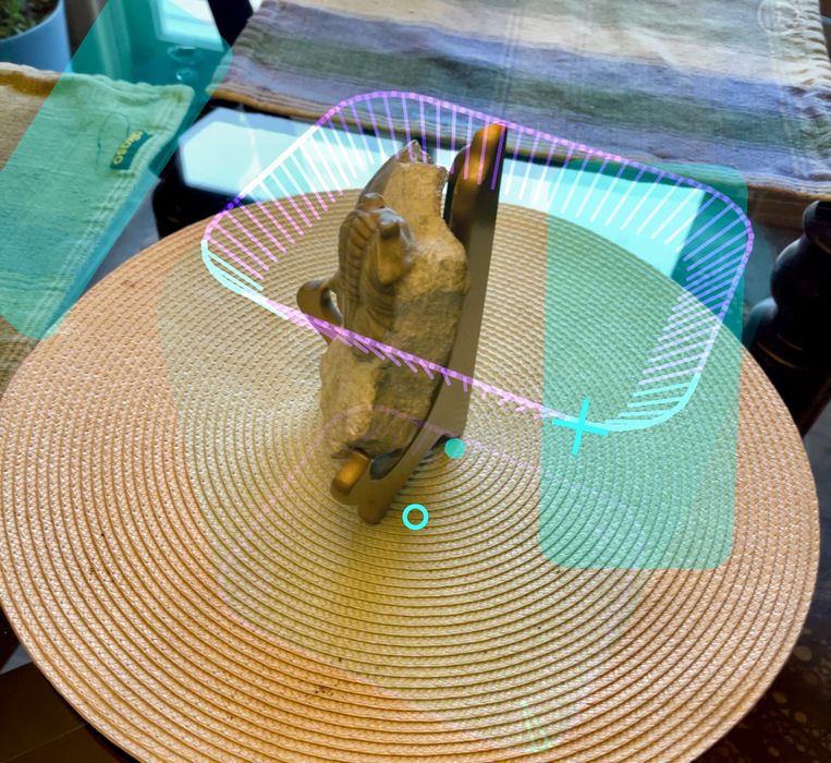 A close-up, top-down shot of a small, sculpted ram's head on a coaster, with digital augmented reality (AR) overlays suggesting a 3D scanning process.
