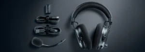 The Razer Blackshark V3 Pro wireless headset laid out on a dark surface with all of its included accessories: the detachable microphone, wireless dongle, and charging cables.